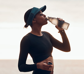 Image showing Drinking water, fitness and black woman by ocean for exercise, marathon training and running. Sports, hydration and female person with liquid in bottle for thirst, cardio workout and body wellness