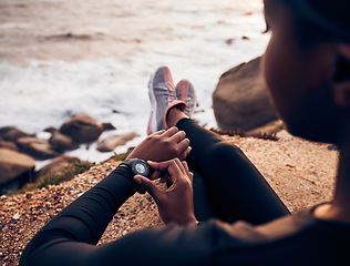 Image showing Relax, running and smart watch with hand of woman on rock for check, fitness tracker and heart rate. Workout, exercise and goal with closeup of female runner at beach for monitor, goals and time