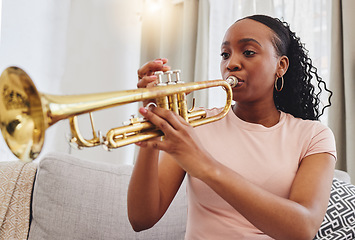 Image showing Music, sofa and woman in home with trumpet, sound and band practice for orchestra concert in living room. Art, creativity and jazz culture, African musician on couch in performance and musical talent