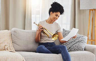 Image showing Woman, music sheet and trumpet in home for learning, practice and classic jazz song. Happy young female person reading paper notes for brass horn instrument, hobby and musical talent in living room