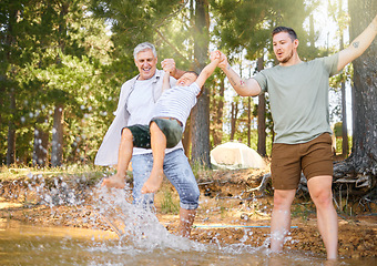 Image showing Hiking, grandfather and dad swinging a boy with a water splash in the forest while on a camping trip together. Children, adventure and a family walking over a river while in the woods or wilderness