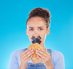 Image showing Burger, diet and woman reject fast food choice and unhappy gives bad, disgust and frustrated review for protection. Disaster, mistake and person disappointed isolated in a studio blue background