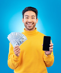 Image showing Money, online and prize with portrait and asian man in blue background with for gambling or profit. Cash, winning and guy with fintech mobile app for competition or celebration with dollar in studio.