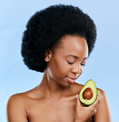 Image showing Face, skincare and avocado with a black woman on a blue background in studio to detox for wellness. Beauty, relax and eyes closed with a natural young female model holding a fruit for antioxidants