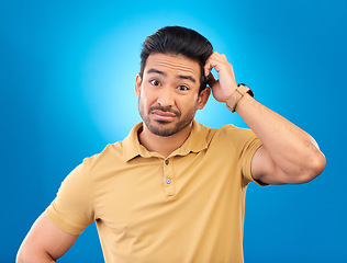 Image showing Portrait, head scratch and man confused over question, doubt or uncertain about problem crisis, error or decision. Studio, face and Asian male person unsure about choice isolated on blue background