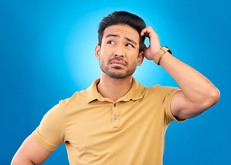 Image showing Thinking, head scratch and man brainstorming solution, problem solving plan or development ideas. Studio, uncertain and confused Asian person with questions, why or doubt on blue background