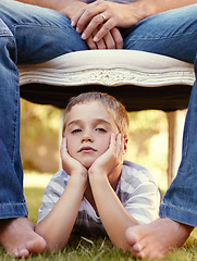 Image showing Bored, face and portrait of child with parent lying on grass for bonding, support and love in outdoor park together. Care, chair and young kid with father or dad on vacation or holiday travel