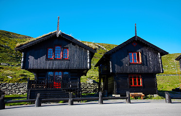 Image showing Houses, wood cabin and cottage in countryside outdoor, building and architecture over blue sky in summer at garden, grass and landscape. Chalet, home exterior and nature, road and street in Norway