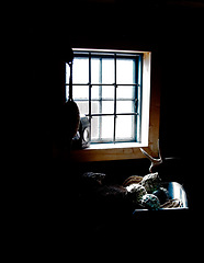 Image showing Dark cabin, interior and light by window in home with gear, tools or fishing equipment, rope or net for storage. Vintage cottage, shed and inside old rustic house, room or abandoned wood architecture