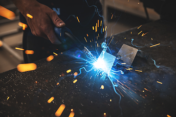 Image showing Male worker hand welding steel rack