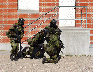 Image showing Camouflage, soldier and training by building with weapon for fitness, exercise or challenge outdoor with gear. Military, people and hiding for target, mission or bootcamp with helmet for survival