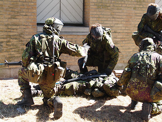 Image showing Army, soldier and team in battle with injury on battlefield, service or training for fitness, exercise or challenge outdoor. Military, people or mission with support for partner, bootcamp or survival