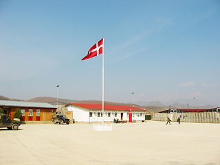 Image showing Denmark, flag and building on landscape with blue sky for military training, bootcamp or government land. Army, base and people outdoor with soldier in countryside for national service and protection