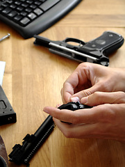 Image showing Man, hands and bullet for a gun at a table with military training, battle and conflict. Army, police and pistol with a male tactical expert of a hero with weapon for shooting range and warrior gear