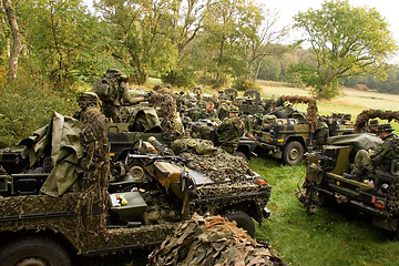 Image showing Soldier, vehicle and military with people in the forest together, getting ready for an ambush during war on the battlefield. Army, training and camouflage with an infantry group on a field of grass