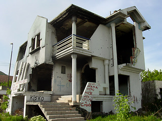 Image showing Abandoned, house and outdoor with war, ruins and destruction of countryside property from bomb disaster. Warzone, land or rubble of grunge apartment, building or old home with graffiti on wall