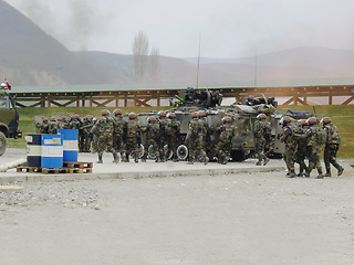 Image showing Military, army and soldier team or back together for mission, order or operation on battlefield or outdoor. Teamwork, squad and bootcamp with camouflage, weapons and vehicles or transport for battle