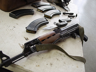 Image showing Gun, rifle and magazines for ammunition of disassembled firearm on table at military base. Closeup of clean army weapon, terrorist or soldier equipment for maintenance, metal or steel barrel on desk