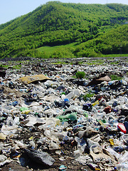 Image showing Pollution, waste or refuse with litter in nature against a green mountain as a danger of climate change. Global warming, garbage and trash, toxic to the environment on an illegal dump or landfill