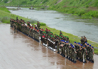 Image showing Military, training or bootcamp with people in the rain for a drill at a parade as a special forces squad. Army, soldier and a group of personnel in camouflage uniform at attention by a river