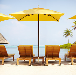 Image showing Tropical, deck chairs and umbrella on beach for luxury, travel or summer villa for vacation or holiday. Maldives, leisure and ocean for resort, relax and island with sunshine, outdoor or caribbean