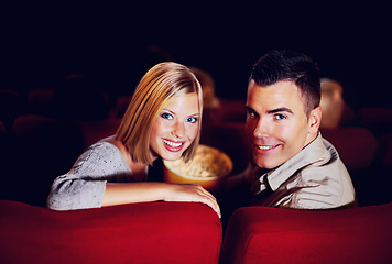 Image showing Cinema, portrait and couple with popcorn on date, watching film or video on romantic night together. Movies, man and woman in theater with snacks, smile and sitting in auditorium to relax in audience