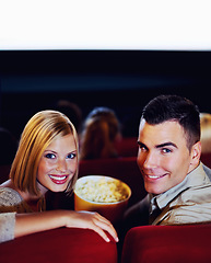 Image showing Cinema, portrait of happy couple with popcorn, watching film or eating on romantic night together. Date, man and woman in movie theater with snacks, smile on face and sitting in auditorium to relax.