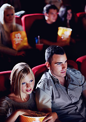 Image showing Cinema, date and couple with popcorn, watching film or eating on romantic night together. Movie, man and woman in theater with snacks, show and sitting in auditorium to relax in evening with partner.