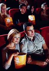 Image showing Cinema, love and couple with popcorn, watching film or eating on romantic date together. Movie night, man and woman in theater with snacks, romance and sitting in auditorium to relax at show premier.