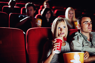 Image showing Seat, popcorn and a couple in the cinema watching a movie for entertainment while on a date. Love, food or romance and young people in a theater audience to experience a film together with a drink