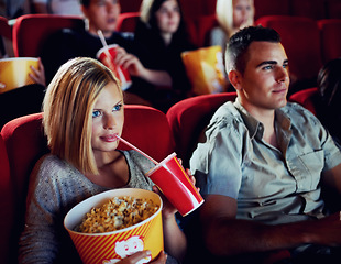 Image showing Popcorn, date and a couple in a cinema together, watching a movie for entertainment or romance. Food, audience or love with a man and woman in theater to experience a film while eating a snack