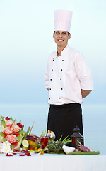 Image showing Happy man, portrait and chef on beach for cooking, resort meal or outdoor catering service. Male person or professional cook smile in fine dining, restaurant or luxury meal, food or water at sea