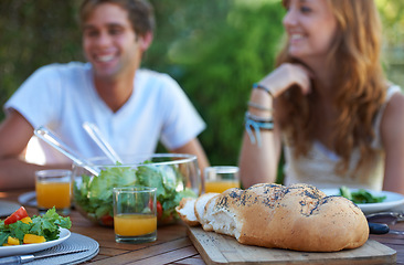 Image showing Friends, bread and food in backyard for lunch and appetizer with a smile and snacks. Salad, talking and young people outdoor of a home with drinks and funny joke together with in summer with meal
