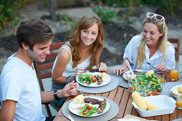 Image showing Friends, eating and bbq food in backyard for lunch and happy event with a smile with reunion. Salad, talking and young people outdoor of a home with communication at a table together with a meal