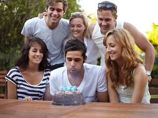 Image showing Birthday, people and blow candles outdoor for celebration, surprise or party with milestone or happiness. Cake, men and women in backyard of home or nature with gathering or social event with smile