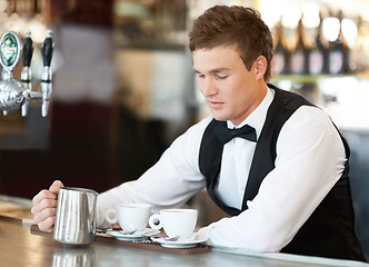 Image showing Coffee, barista and young man waiter in cafe making a latte, espresso or cappuccino at an event. Hospitality, server and male butler preparing a warm beverage in a mug or cup by a bar in restaurant.