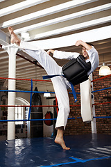 Image showing Man, karate and high kick in training, self defense or jiujitsu for martial arts or fighting match. Male person, athlete or fighter in MMA boxing, muay thai or fitness practice at dojo or gym ring