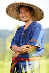 Image showing Asian man, portrait and straw hat in farming, wheat or agriculture on rice field in outdoor nature. Happy male person or Thai smile on farm in plantation, gathering or natural sustainability on land