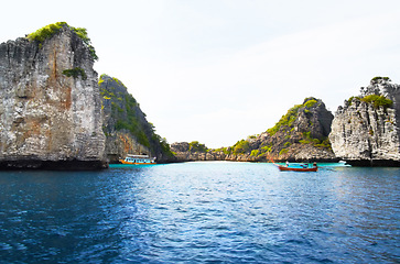 Image showing Island, ocean and mountains background for tropical, adventure and holiday with boats, journey and travel. Outdoor, nature and landscape of blue water, calm sea and rocks or cliff for secret vacation