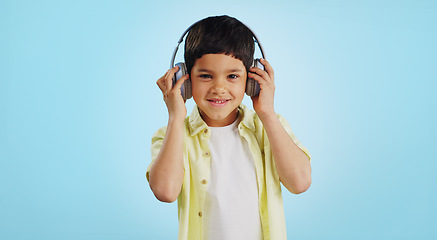 Image showing Kid, dancing and listening to music in studio with smile on blue background in mockup for fun, promotion and summer. Youth, boy or person with headphones for app, streaming or game on social media