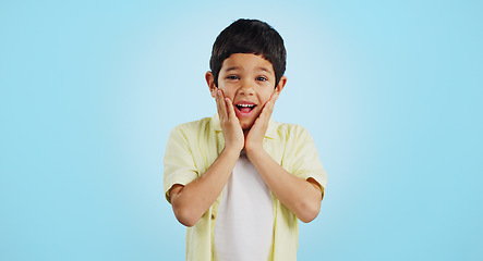 Image showing Smile, kid and hands on face for surprise in studio isolated on a blue background mockup space. Portrait, wow and happy child shocked at good news, promo announcement and excited facial expression