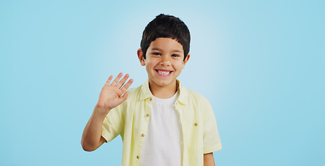 Image showing Kid, hand and waving with smile in studio on blue background in mockup with excitement. Youth, boy and greeting while looking at screen with face for announcement of offer on social media, web or app