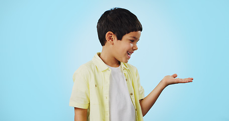 Image showing Kid, smile and happy for presentation in studio on blue background with mockup for product placement. Youth, boy and excited for opportunity, offer or deal on app, social media or digital marketing