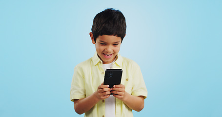 Image showing Kid, phone or typing to chat in studio on social media to play mobile games or download app. Blue background, scroll or boy child reading notification for online communication or watch fun multimedia