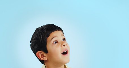 Image showing Surprise, boy and child with decision, opportunity and fantasy on a blue studio background. Person, mockup space and happy kid looking up, future and announcement with shock, expression and emoji