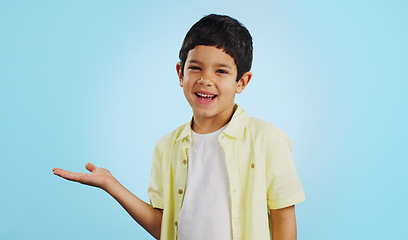 Image showing Kid, smile and happy for presentation in studio on blue background with mockup for product placement. Youth, boy and excited for opportunity, offer or deal on app, social media or digital marketing