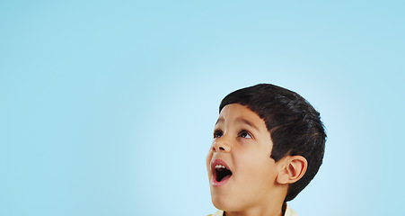 Image showing Surprise, boy and child with decision, opportunity and fantasy on a blue studio background. Person, mockup space and happy kid looking up, future and announcement with shock, expression and emoji