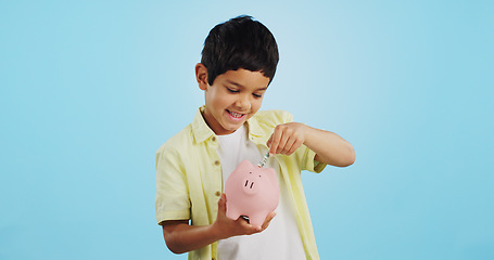 Image showing Piggy bank, cash and child face with money, savings and cash planning in a studio, Happy, portrait and young boy with allowance and safe for bills, wealth and budget with blue background and smile