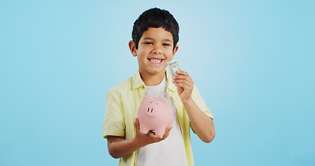 Image showing Piggy bank, cash and child face with money, savings and cash planning in a studio, Happy, portrait and young boy with allowance and safe for bills, wealth and budget with blue background and smile