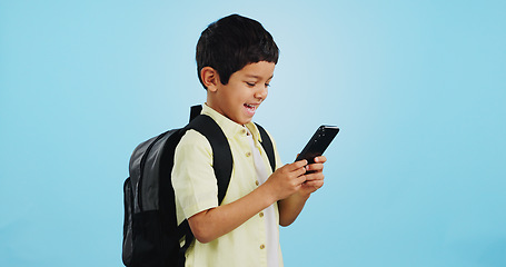 Image showing School, phone or kid on social media in studio typing to chat, play mobile games or download app. Blue background, student or happy boy child reading notification for online education or tech search